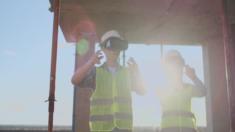 Two-contemporary-crew-workers-using-VR-to-visualize-projects-standing-in-unfinished-building-on-construction-site-copy-space